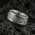 Load image into Gallery viewer, Polished silver spinner ring on volcanic stone, crisp macro photo emphasizing smooth edges, clean reflections, and sharp knotwork engraving depth.