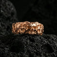 Load image into Gallery viewer, Rose gold plated skull ring on volcanic stone, refined macro close-up showcasing soft rose sheen across the skull motif and decorative scroll pattern.