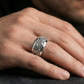 Load image into Gallery viewer, Polished silver cross scrollwork band ring worn on the finger, lifestyle photo featuring a sleek reflective finish and ornate cross pattern for daily statement wear.