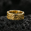 Load image into Gallery viewer, Gold plated quatrefoil cross band ring on volcanic stone, luxury macro shot capturing warm gold tone across the central cross emblems and flowing filigree lines.