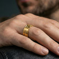 Load image into Gallery viewer, Gold plated cross band ring worn on the finger, lifestyle shot featuring rich golden glow and a strong cross centerpiece for standout everyday wear.