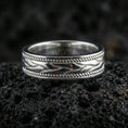 Load image into Gallery viewer, Sterling silver wave band ring on black volcanic stone, shown in a polished silver look with crisp highlights along the flowing waves and twisted rope edges.