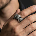 Load image into Gallery viewer, Eagle head and wing sterling silver ring worn on a finger, oxidized finish delivering bold contrast and pronounced wing texture.