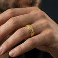 Load image into Gallery viewer, Gold plated textured wedding band worn on finger, repeating starburst floral engraving, premium lifestyle jewelry photo.