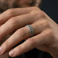 Load image into Gallery viewer, Oxidized sterling silver wedding band worn on finger, starburst floral engraved texture, natural lifestyle hand shot.