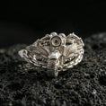 Load image into Gallery viewer, Polished silver biker ring with motorcycle and wing details wrapped in chain links on porous volcanic stone, close-up showing clean shine and sharp sculpted lines