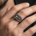 Load image into Gallery viewer, Oxidized motorcycle chain ring worn on a finger, close-up lifestyle shot showing winged bike motif, darkened recesses and rugged biker statement look