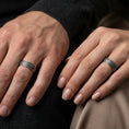 Load image into Gallery viewer, Oxidized sterling silver geometric band worn on finger, interlocking pattern detail, natural lifestyle hand shot with shallow depth of field.