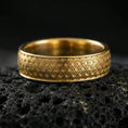 Load image into Gallery viewer, Gold plated geometric pattern band ring on volcanic rock, detailed interlocking motif with clean borders, luxury jewelry product photography.
