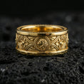 Load image into Gallery viewer, Gold plated lion medallion band ring on volcanic rock, bold central lion relief with decorative pattern borders, luxury jewelry product photography.