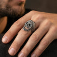 Load image into Gallery viewer, Oxidized filigree skull ring worn on a finger, close-up lifestyle shot showing darkened recesses, ornate baroque carving and bold gothic statement look