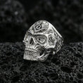 Load image into Gallery viewer, Polished silver skull ring featuring a square and compass “G” symbol on top and engraved scrollwork sides, photographed on porous volcanic stone