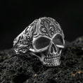 Load image into Gallery viewer, Oxidized sterling silver filigree skull ring with ornate scroll engravings, photographed on black volcanic rock in a dark macro studio setting