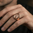 Load image into Gallery viewer, Rose gold plated raven crest signet ring worn on a finger, close-up lifestyle photo showing ornate relief and statement silhouette