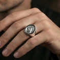Load image into Gallery viewer, Polished silver raven crest signet ring on the finger, wearable shot emphasizing clean shine and detailed engraving lines