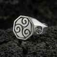 Load image into Gallery viewer, Polished silver octagonal signet ring featuring a bold Celtic triskelion symbol and side swirl detail, close-up product shot on volcanic stone