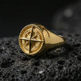 Load image into Gallery viewer, Gold plated compass signet ring with raised wind rose star, directional letters, and dotted frame detail, macro image on black volcanic rock