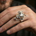 Load image into Gallery viewer, Polished silver horned skull ring on the finger, wearable shot focusing on the sculpted teeth and horn texture