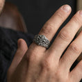 Load image into Gallery viewer, Oxidized fleur-de-lis signet ring worn on a finger, lifestyle close-up highlighting the leaf engravings and crest detail