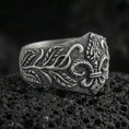Load image into Gallery viewer, Oxidized sterling silver fleur-de-lis signet ring with engraved vine leaves and textured band, macro photo on black volcanic rock