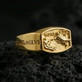 Load image into Gallery viewer, Gold plated Archangel Michael signet ring with Roman numeral MDXI and detailed relief artwork, product-only macro shot on black volcanic rock