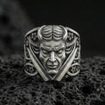 Load image into Gallery viewer, Oxidized sterling silver devil face signet ring with crossed blades and ornate floral accents, macro product photo on black volcanic rock