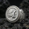 Load image into Gallery viewer, Polished silver ancient coin signet ring with a Roman-style emperor profile and twisted rope bezel, close-up on volcanic stone