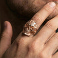 Load image into Gallery viewer, Rose gold plated biomechanical skull ring on the finger, close-up lifestyle image showing the cyber skull relief and metal texture