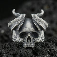 Load image into Gallery viewer, Oxidized sterling silver horned skull ring with curved ram-style horns and deep shadowed details, macro photo on black volcanic rock