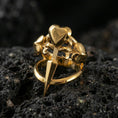 Load image into Gallery viewer, Gold plated heart dagger ring with a sharp dagger silhouette and heart-shaped top detail, product-only macro on black volcanic rock