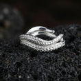 Load image into Gallery viewer, Polished silver octopus tentacle open band ring on black volcanic stone, crisp suction cup engraving and curved wrap design, centered close-up studio lighting.