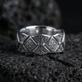 Load image into Gallery viewer, Polished silver engraved geometric band ring on black volcanic stone, crisp diamond motifs and ornate filigree engraving, centered close-up studio lighting.