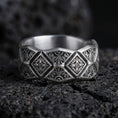 Load image into Gallery viewer, Oxidized sterling silver engraved ornament band ring on dark volcanic rock, raised diamond panels with scrollwork detail, premium macro product shot.