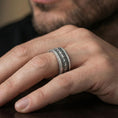 Load image into Gallery viewer, Oxidized sterling silver serpent skin band worn on finger, scaled texture detail with rope edge border, natural lifestyle hand shot with shallow depth of field.