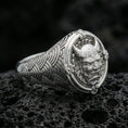 Load image into Gallery viewer, Polished silver oni mask ring featuring seigaiha wave pattern shoulders and framed horned demon face, close-up on dark volcanic stone