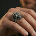 Load image into Gallery viewer, Oxidized finish skull ring worn on a finger, cap-and-glasses skull design shown in a close-up lifestyle shot