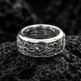 Load image into Gallery viewer, Polished silver fidget spinner wave band ring on black volcanic stone, crisp ocean scrollwork texture and smooth comfort edges, centered close-up studio lighting.