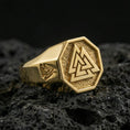 Load image into Gallery viewer, Sterling silver Valknut signet ring with a gold plated finish, octagon face showing the Valknut Norse symbol over a dark textured background, macro on volcanic rock