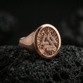 Load image into Gallery viewer, Sterling silver Valknut signet ring with a rose gold plated finish, circular signet face with the Norse Valknut symbol and detailed etched texture, close-up on volcanic rock