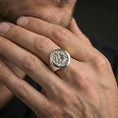 Load image into Gallery viewer, Polished silver finish Valknut signet ring on the finger, macro lifestyle image highlighting the circular face and textured Norse motif