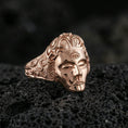 Load image into Gallery viewer, Sterling silver third eye face ring with a rose gold plated finish, sculpted face and third eye symbol with decorative engraved sides, close-up on volcanic rock