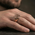 Load image into Gallery viewer, Rose gold plated finish triquetra Celtic knot signet ring on the finger, macro lifestyle shot focusing on the raised knot symbol and smooth band