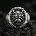 Load image into Gallery viewer, Oxidized sterling silver oni mask signet ring on porous volcanic rock, macro view showing high relief facial details