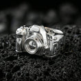 Load image into Gallery viewer, Sterling silver camera signet ring in a polished silver finish, sculpted retro camera body with raised lens and dials, close-up on volcanic stone