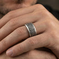 Load image into Gallery viewer, Oxidized sterling silver elven star spinner band worn on finger, Celtic knotwork and star motif detail on rotating center, natural lifestyle hand shot with shallow depth of field.