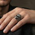 Load image into Gallery viewer, Oxidized finish sterling silver masonic skull ring worn on a finger, close-up lifestyle shot highlighting the engraved skull face and all-seeing eye triangle detail