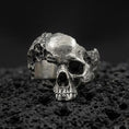 Load image into Gallery viewer, Sterling silver shattered skull ring with an oxidized finish, openwork skull design and rugged gothic texture, macro on black volcanic rock