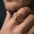 Load image into Gallery viewer, Rose gold plated finish Masonic skull ring on a finger, macro lifestyle shot showcasing the detailed scrollwork, skull centerpiece and symbolic gothic styling