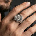 Load image into Gallery viewer, Sterling silver octagonal cross ring on a finger, macro lifestyle image emphasizing the polished silver finish and engraved ornamental band details