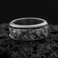 Load image into Gallery viewer, Oxidized sterling silver bear scene band ring on dark volcanic rock, detailed woodland bear relief with Celtic knot side accents, premium macro product shot.